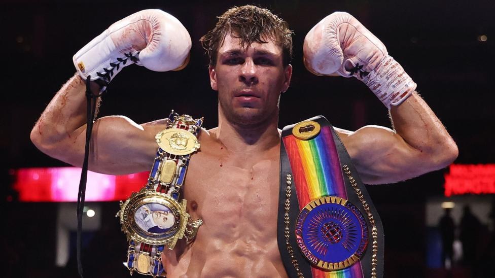 Constantin Ursu poses with a belt on either shoulder following a fight